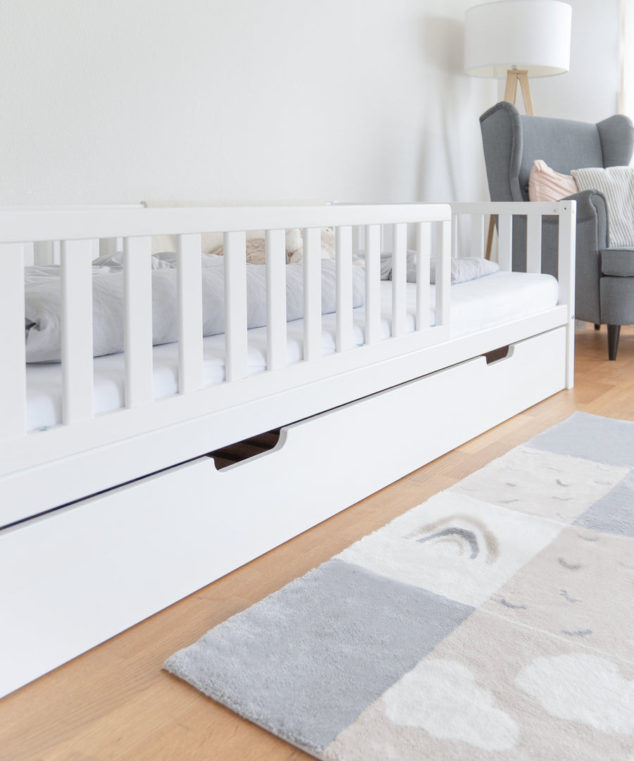Zusätzlicher Schlafplatz*Unser optionaler Bettkasten bietet weitere Stauraumfläche oder einen extra Schlafplatz.|Nahaufnahme Bettkasten weiß für Kinderbett Buche.