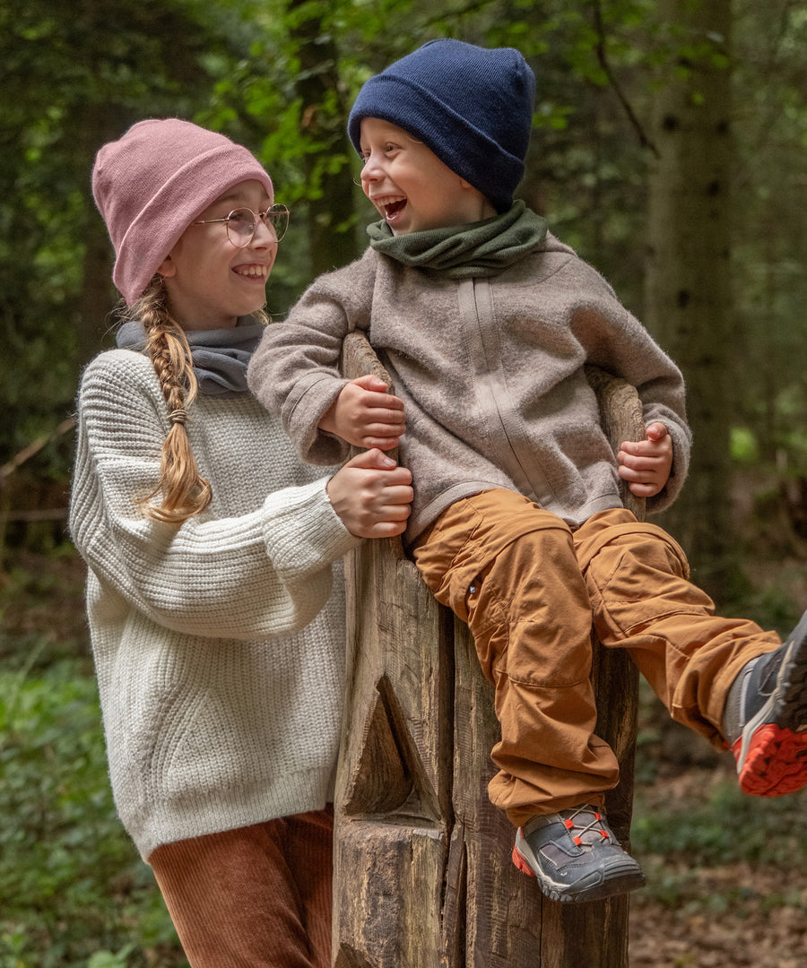 Vielseitig kombinierbar*Der Kinderschal im zeitlosen Design ist vielseitig kombinierbar und in wunderschönen Farben erhältlich.|Zwei Kinder mit Schlauchschal und Strickmütze im Wald.