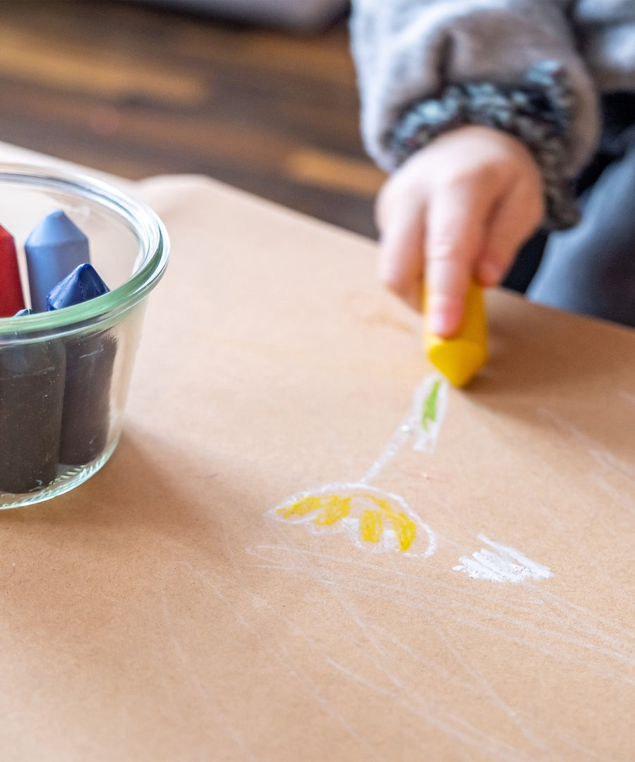 Für Kinder gemacht*Dank der 100 % natürlichen Inhaltsstoffe sind die Stifte für dein Kinder unbedenklich im Kontakt mit Mund und Haut.|Kind malt eine gelbe Blume mit den Wachsmalstiften.