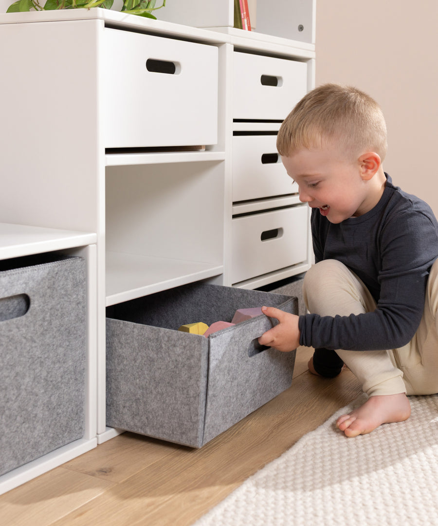Einfach herausziehen*Die seitliche Grifföffnung erleichtert das Herausziehen, Hochheben und Tragen der Filzbox im Familienalltag.|Kind zieht selbstständig die Filzbox aus dem Aufbewahrungssystem.