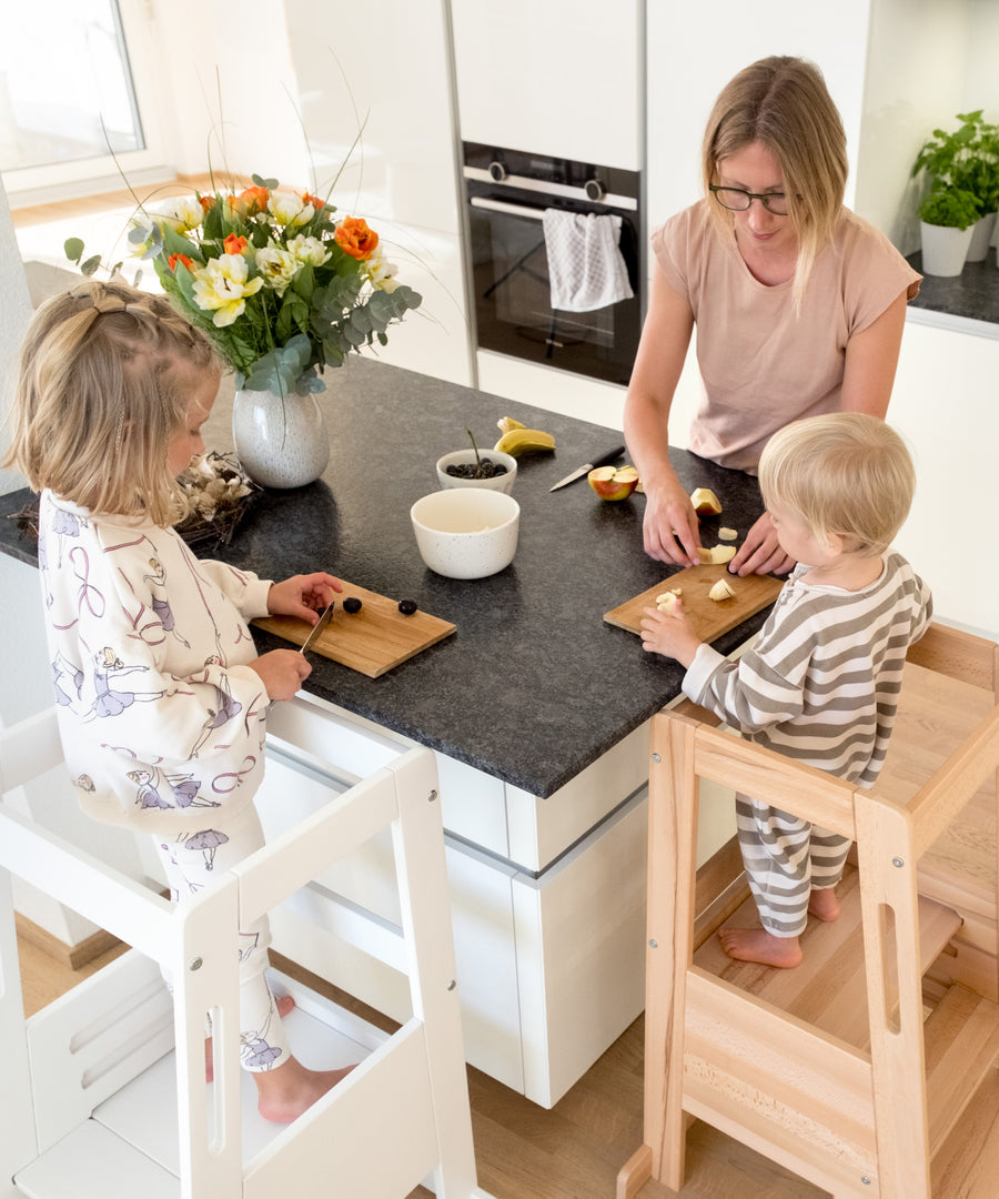 Kinder stehen in den Lerntürmen und helfen beim Kochen in der Küche.