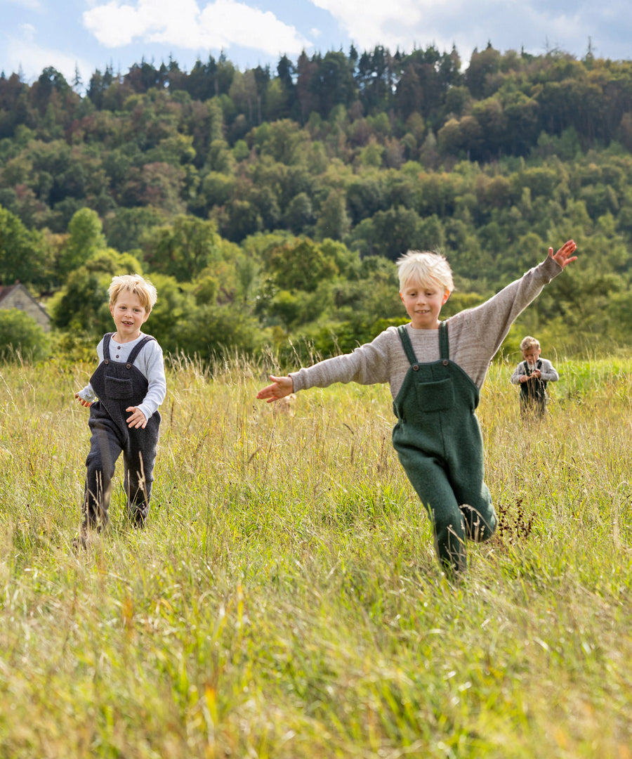 Große Bewegungsfreiheit*Die bequeme Outdoor-Hose ist dehnbar und punktet mit geringem Gewicht – für viel Freiheit beim Spielen.|Kinder spielen im Feld und tragen die Walk-Latzhosen.