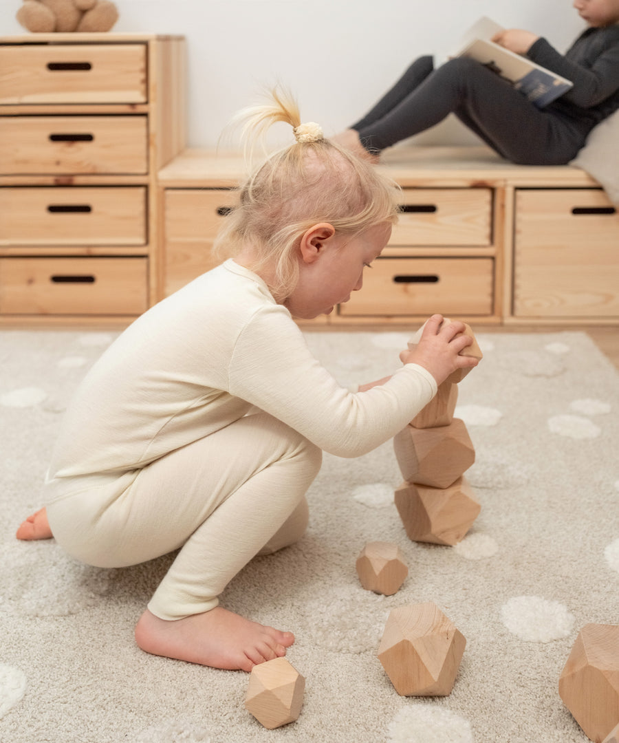 Für empfindliche Kinderhaut*Die Funktionsunterwäsche aus Merino ist aufgrund des feinen Stricks besonders kuschelig und somit perfekt für sensible Kinderhaut.|Kind spielt in Merino Set natur.
