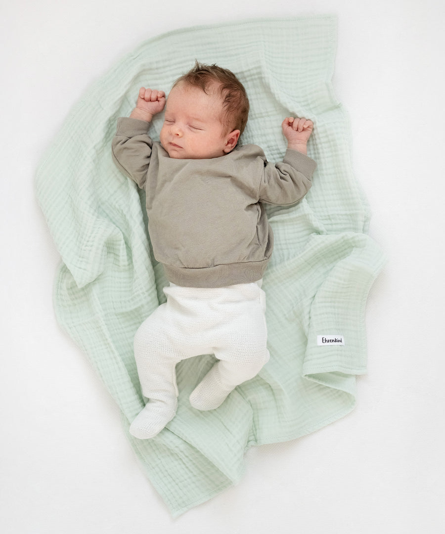 Kuschelige Alleskönner*Unsere Mulltücher im 4er-Set in der Größe von ca. 70 × 70 cm sind wahre Multitalente und gehören in jede Baby-Erstausstattung.|Baby liegt auf Mulltuch in Jade aus dem Mulltücher-Set Blau.
