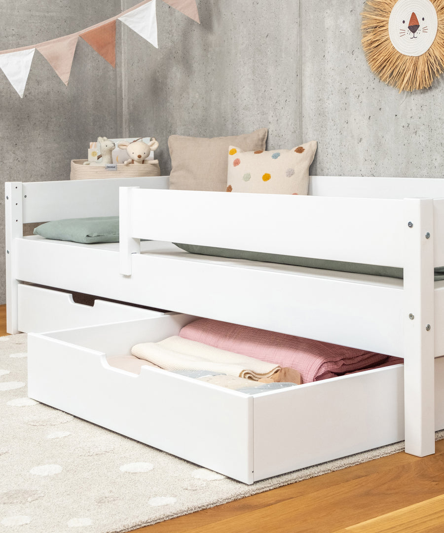 Ehrenkind Kinderbett  weiß mit offener Schublade.