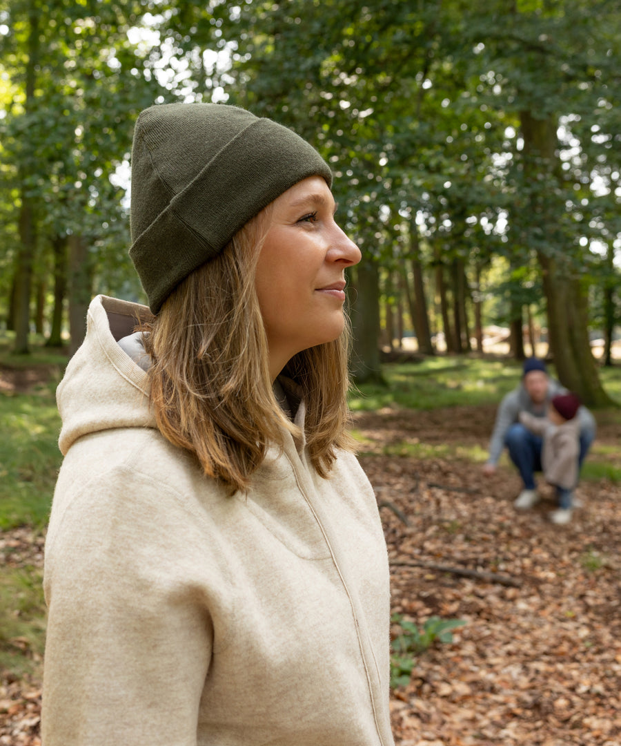 Warm durch Herbst & Winter*Die weiche Strickmütze aus 100 % Bio-Merinowolle schützt vor Kälte und Wind.| Frau trägt die Strickmütze in Olivgrün.