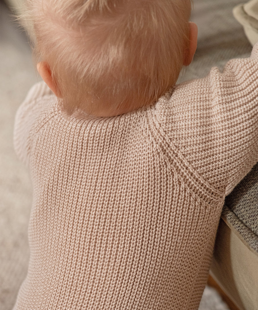 Feines Strickmuster des Strickoveralls in Nahaufnahme am Baby.