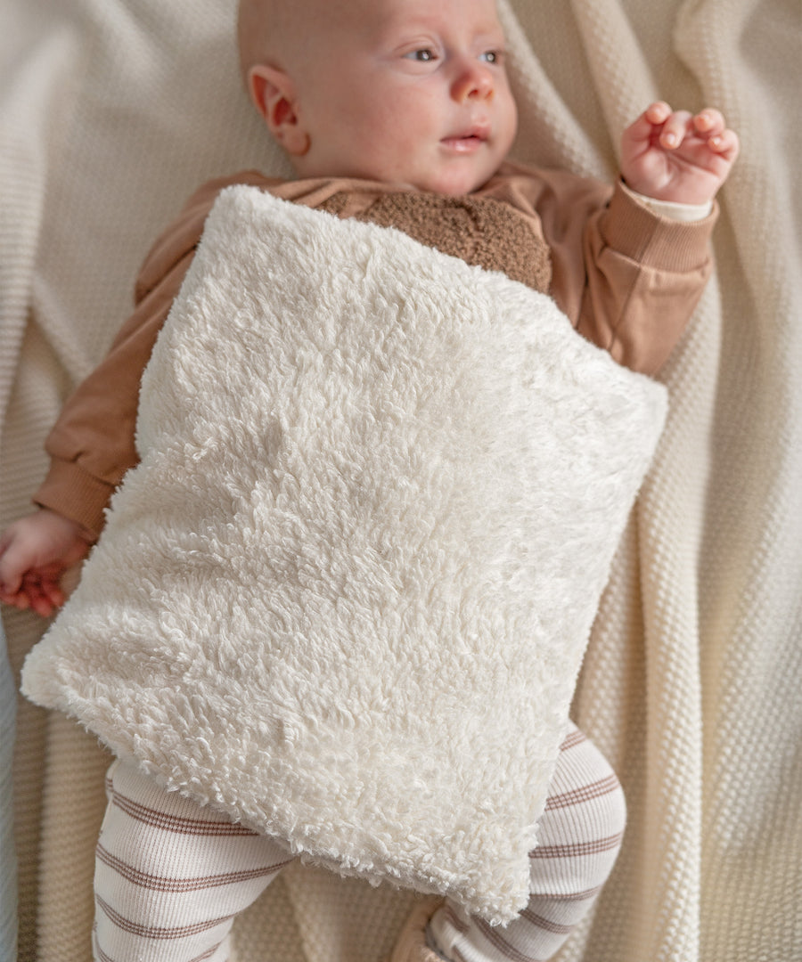 Baby kuschelt mit weichem Teddy-Wärmekissen aus Bio-Baumwolle – wohltuende Wärme für kleine Körper.